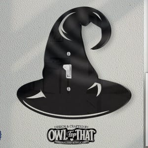 May include: A black metal witch hat light switch cover with a pointed top and a wide brim. The switch cover is designed to fit over a standard light switch or outlet. The text "OWL TOP THAT" is printed below the switch cover.
