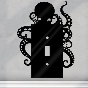 May include: Black octopus light switch cover. The design shows a stylized octopus wrapping around the rectangular cover, with the switch and screw holes visible. The tentacles have suction cups. A decorative accent for nautical or sea-themed decor.