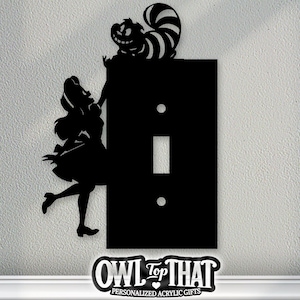 May include: Black acrylic light switch cover featuring Alice in Wonderland characters. The design includes Alice, the Cheshire Cat, and the text "OWL Top THAT". A decorative and personalized acrylic gift.
