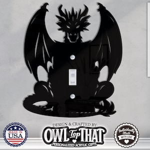 Op de afbeelding: Zwarte acryl draak lichtschakelaar cover. De draak heeft grote vleugels en is gecentreerd op de cover. De cover heeft een witte schakelaar en twee schroeven. De tekst "DESIGN & CRAFTED BY: OWL TOP THAT PERSONALIZED ACRYLIC GIFTS" staat onderaan.