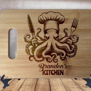 Può includere: Tagliere rettangolare in bambù con un'apertura per l'impugnatura. Il tagliere presenta un polpo inciso con un cappello da chef, che tiene un coltello e una forchetta. Il testo "Brandon's KITCHEN" è sotto.