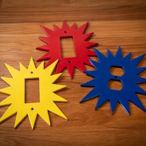 Pode incluir: Três capas decorativas em forma de estrela para interruptores e tomadas, nas cores vermelho, amarelo e azul. Feitas de material brilhante, adaptam-se a interruptores e tomadas padrão, adicionando um toque decorativo.