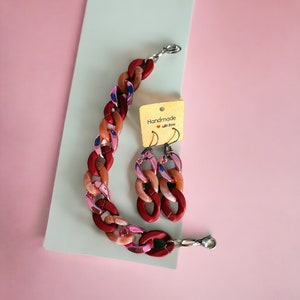 May include: A set of pink and red chunky chain earrings and a matching necklace. The jewelry is handmade and comes with a tag that says "Handmade with love".