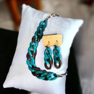 May include: A turquoise and brown chain necklace and matching earrings. The necklace is made of large, chunky links and the earrings are long and dangle.