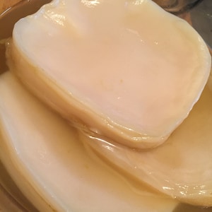 May include: Close-up of several pale, translucent kombucha SCOBYs, layered in a glass container. The SCOBYs have a smooth, slightly textured surface and a light, creamy color. The liquid surrounding the SCOBYs is a light amber color.
