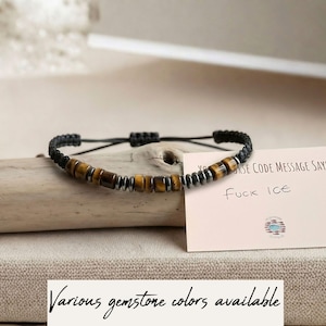 Könnte beinhalten: Ein schwarzes Makramee-Armband mit Tigerauge- und silberfarbenen Perlen. Eine Karte neben dem Armband lautet "Morse Code Message Says: Fuck Ice". Der untere Teil des Bildes lautet "Various gemstone colors available".