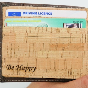 Inside of personalised cork wallet is  engraved "Be happy". Open wallet displaying card slots holding cards.