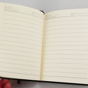 Vegan notebook in hand open to display undated, lined pages.