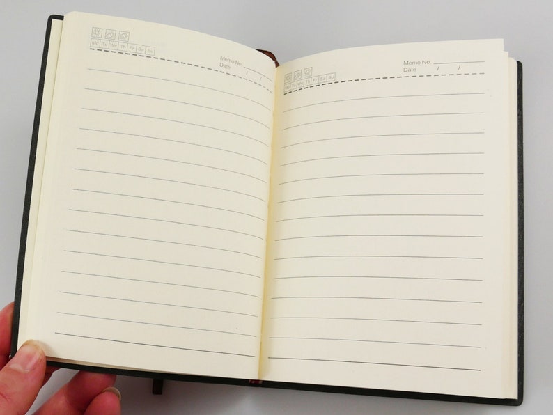 A vegan notebook in hand open to display undated, lined pages.