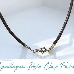 May include: A brown leather cord necklace with a silver lobster clasp fastening. Hypoallergenic.