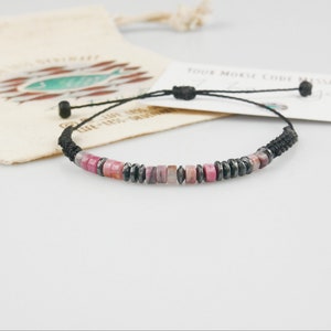 Pink jade and Hematite bracelet with customised Morse code message, photographed with branded hemp gift bag and message card blurred in the background.