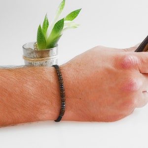Bamboo and beaded bracelet with Morse code message, pictured close up on male model’s arm.