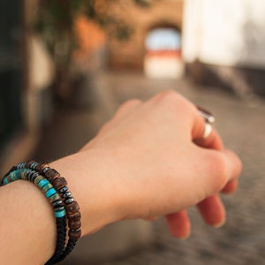 Double stacked Morse code bracelets with Turquoise and wooden beads, pictured on model's wrist with blurred street background.