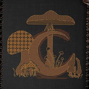 Könnte beinhalten: Ein Kreuzstichmuster mit einem Pilzmond mit einer Halbmondform und Pilzen in einem braunen und goldenen Farbschema. Das Muster ist in einem schwarzen, verzierten Rahmen gerahmt und der Text "Mushroom Moon" und "Urban Stitches" ist sichtbar.