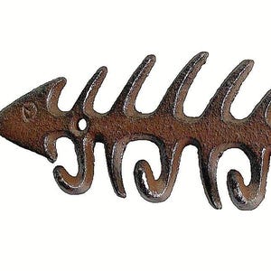 May include: A rustic, brown metal fishbone-shaped wall hook with five curved hooks. The decorative piece features a detailed design of a fish skeleton, perfect for coastal or nautical decor.