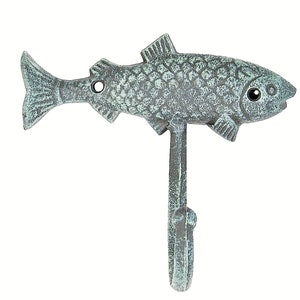 May include: A cast iron fish-shaped wall hook with a distressed, verdigris finish. The hook features a detailed fish design with scales, fins, and an eye. The hook extends downward from the fish's body, providing a functional and decorative element.