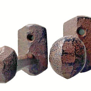 May include: A set of four rustic, brown metal cabinet knobs and pulls. Two are faceted spheres, and two are rectangular with a circular hole. The hardware has a weathered, aged appearance, suggesting a vintage or industrial style.