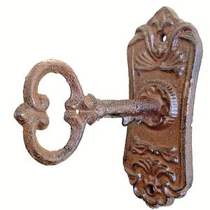 May include: A cast iron key-shaped wall hook with an ornate design. The hook is rusty brown in color and has a decorative scrollwork pattern.
