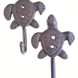 May include: Two cast iron turtle hooks in a dark brown finish. The hooks are shaped like sea turtles with a detailed shell design.