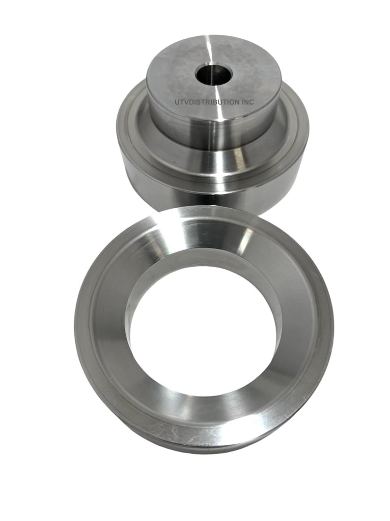 May include: Two silver metal rings, one stacked on top of the other. The top ring has a smaller hole in the center and the text "UTVDISTRIBUTION INC" is printed on the side.