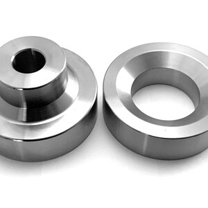May include: Two silver metal spacers, one with a centre hole and the other with a bevelled edge.