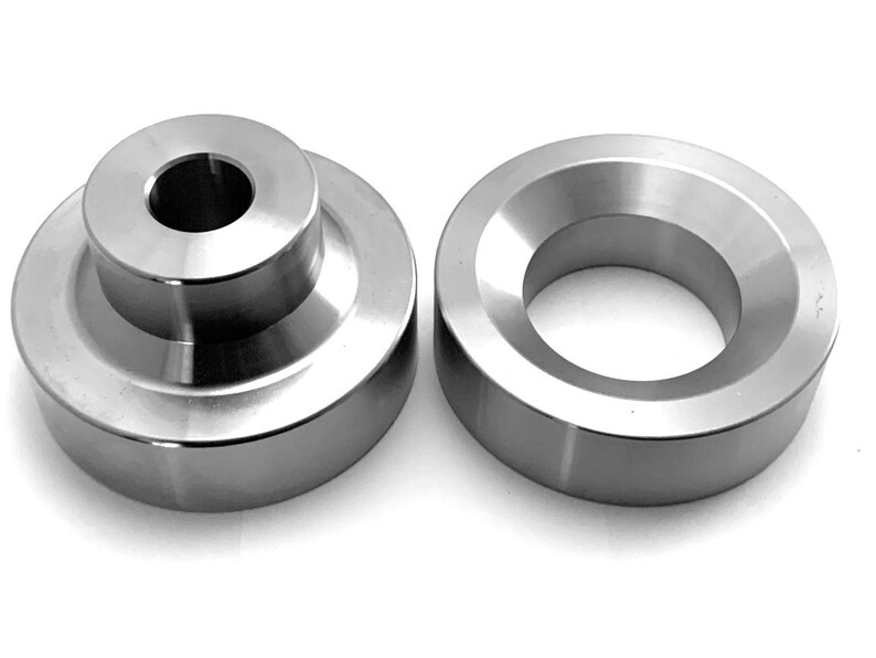 May include: Two silver metal spacers, one with a centre hole and the other with a bevelled edge.