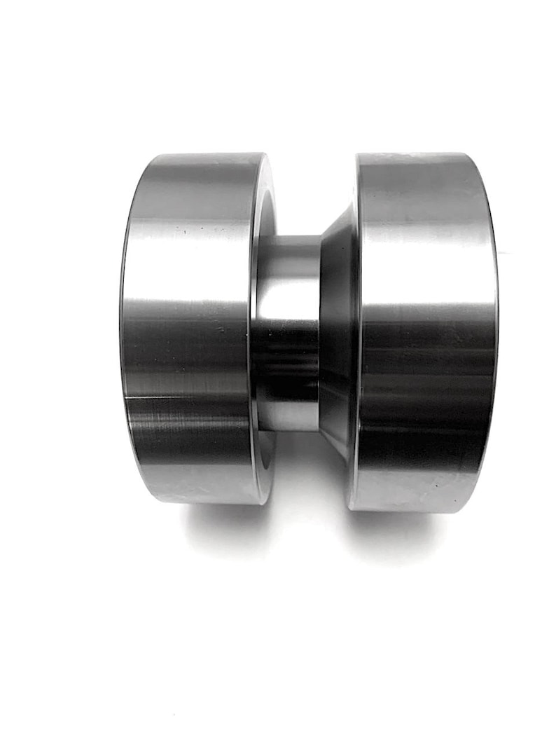May include: A silver metal roller with a smooth, cylindrical shape. The roller has a slightly smaller diameter in the middle, creating a slight hourglass shape.