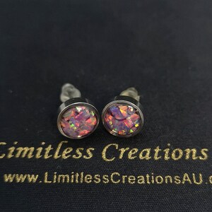 May include: A pair of silver stud earrings with pink and orange opal-like stones. The earrings are on a black background with the text "Limitless Creations AU" and "www.LimitlessCreationsAU.com".