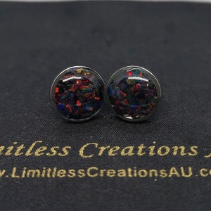 May include: A pair of silver stud earrings with black, red and blue glitter embedded in the resin.