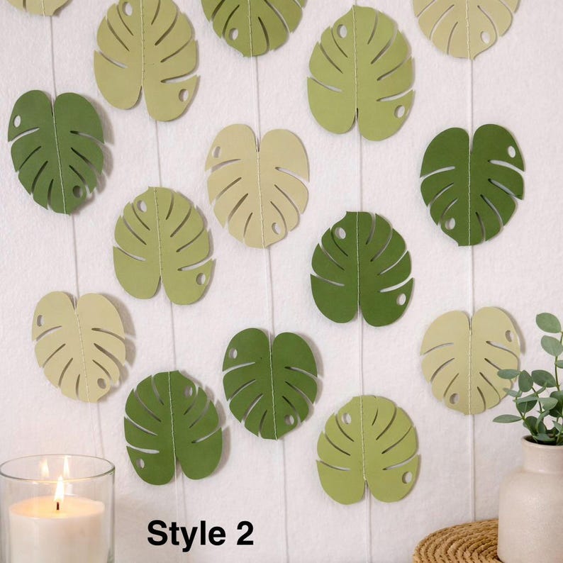 K&ouml;nnte beinhalten: Dekorative Monstera-Bl&auml;tter aus Papier in verschiedenen Gr&uuml;n- und Cremet&ouml;nen, angeordnet vor einem wei&szlig;en Hintergrund. Die Bl&auml;tter sind mit detaillierten Adern und einem Loch am Stiel versehen. Der Text "Style 2" ist unten zu sehen.