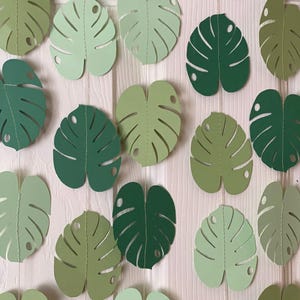 K&ouml;nnte beinhalten: Girlanden aus Papierbl&auml;ttern in verschiedenen Gr&uuml;nt&ouml;nen, von hell bis dunkel. Die Bl&auml;tter sind in Form von Monstera-Bl&auml;ttern ausgeschnitten und aufgereiht. Der Text "Style 1" ist unten sichtbar.