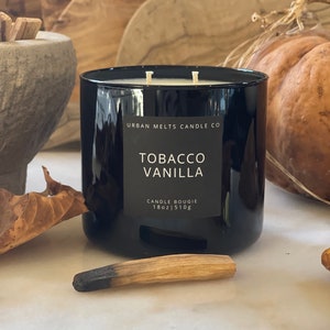 Puede incluir: Vela negra de vidrio con una etiqueta blanca que dice "Urban Melts Candle Co. Tobacco Vanilla Candle Bougie 18oz | 510g"