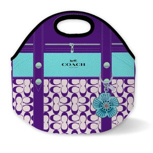 May include: Purple and white Coach lunch bag with a blue flower charm. The bag has a zipper closure and a top handle.