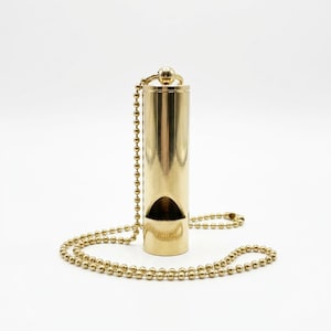Könnte beinhalten: Eine goldfarbene Pfeife mit einer Kugelkette. Die Pfeife ist zylindrisch mit einer gebogenen Öffnung. Kette und Pfeife haben eine glänzende, metallische Oberfläche. Der Hintergrund ist schlicht weiß.