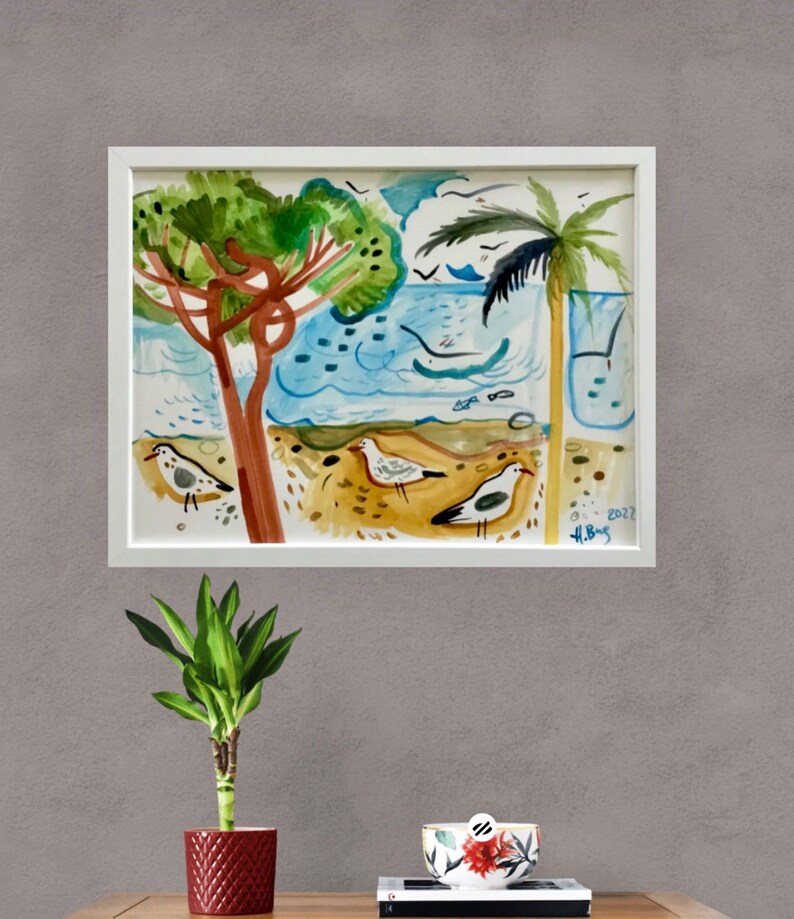 May include: A watercolor painting of a beach scene with palm trees, seagulls, and waves. The painting is framed in a white frame and has the artist's signature and the year 2022 in the bottom right corner.