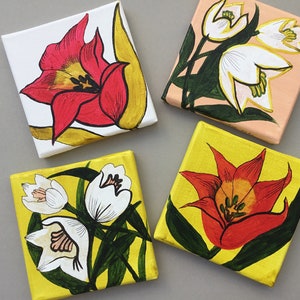 May include: Four small square canvases with painted floral designs. Two canvases feature red tulips on a white background with gold accents. The other two canvases feature white flowers on a yellow background with green leaves.