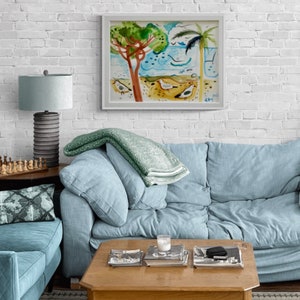 May include: A light blue sofa with a green throw blanket, a white lamp with a gray base, and a wooden coffee table with books and a glass on top. A framed watercolor painting of a beach scene with palm trees and birds hangs on a white brick wall.