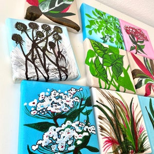 May include: Nine small square canvases with painted floral and foliage designs. The canvases are arranged in a grid pattern and feature a variety of colors, including green, pink, red, white, and blue.