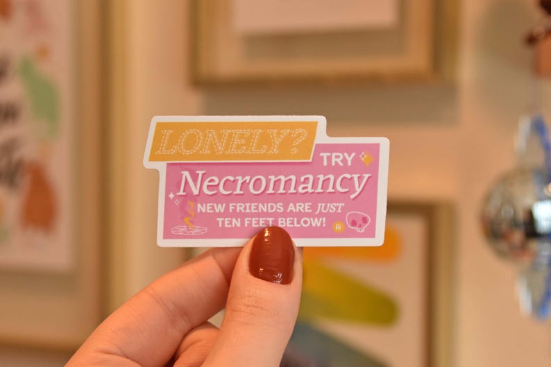 A die cut vinyl sticker in a typographic design. It reads "Lonely? Try Necromancy. New friends are just ten feet below!" A friendly looking skull says "Hi" alongside a summoning circle with swirling magic. The finish is matte and waterproof.