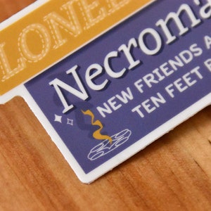 A die cut vinyl sticker in a typographic design. It reads "Lonely? Try Necromancy. New friends are just ten feet below!" A friendly looking skull says "Hi" alongside a summoning circle with swirling magic. The finish is matte and waterproof.