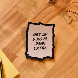 May include: A white sticker with black borders and a comic book style font. The sticker says "Get Up & Move, Damn Extra."