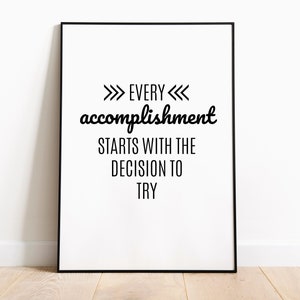 May include: Black and white motivational quote poster with the text "Every accomplishment starts with the decision to try" framed in a black frame.