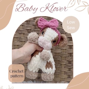 Puede incluir: Un peluche de vaca de ganchillo con manchas marrones y blancas, con un lazo rosa. El texto "Baby Klover" está encima de la vaca. También se ven las palabras "Low Sew" y "Crochet pattern".