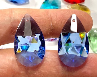 May include: Two teardrop-shaped crystal pendants with a hole at the top for hanging. The pendants are a light blue color and have a faceted design.