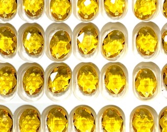 May include: A close-up view of a sheet of clear plastic packaging filled with small, round, yellow glass beads. The beads are arranged in rows and columns, and they are all the same size and shape.