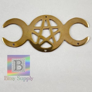May include: A gold-toned metal charm featuring a triple moon symbol with a pentagram inside the center circle.