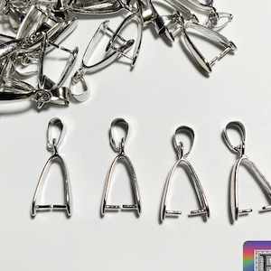 Może przedstawiać: Srebrne zawieszki do zawieszek, rodzaj elementu jubilerskiego, pokazane są w stosach i pojedynczo. Zawieszki mają kształt trójkąta z pętlą na górze. Zawieszki służą do mocowania zawieszek do naszyjników lub bransoletek.