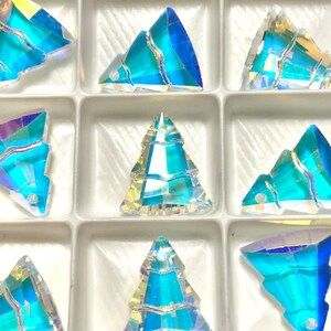 May include: A set of 12 iridescent blue crystal Christmas tree charms. The charms are arranged in a clear plastic storage box. The box has a white background and the text "Set of 12" is printed on the bottom right corner.