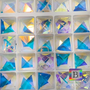 K&ouml;nnte beinhalten: Nahaufnahme einer Vielzahl von regenbogenfarbenen blauen quadratischen Strasssteinen in einem wei&szlig;en Plastikbeh&auml;lter. Die Strasssteine sind in Reihen und Spalten angeordnet.