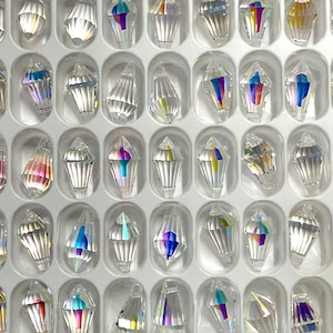 Peut inclure: Une vue rapproch&eacute;e d'une grille de 36 formes de larmes de cristal en verre transparent. Les cristaux sont dispos&eacute;s en rang&eacute;es et en colonnes, et ils sont tous de la m&ecirc;me taille et de la m&ecirc;me forme.